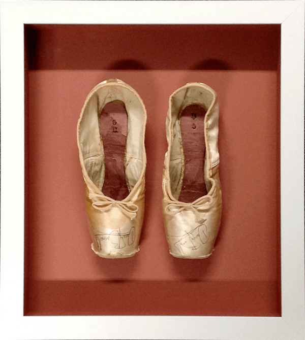 A pair of Darcy Bussell ballet slippers displayed in a frame
