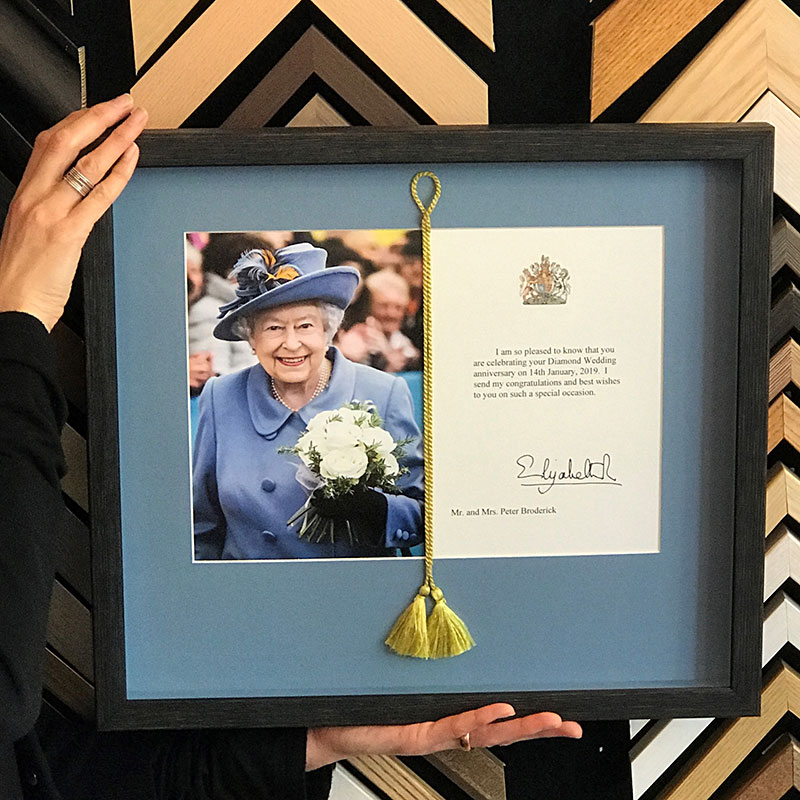 Diamond wedding anniversary card received from the queen on a blue background with a black frame