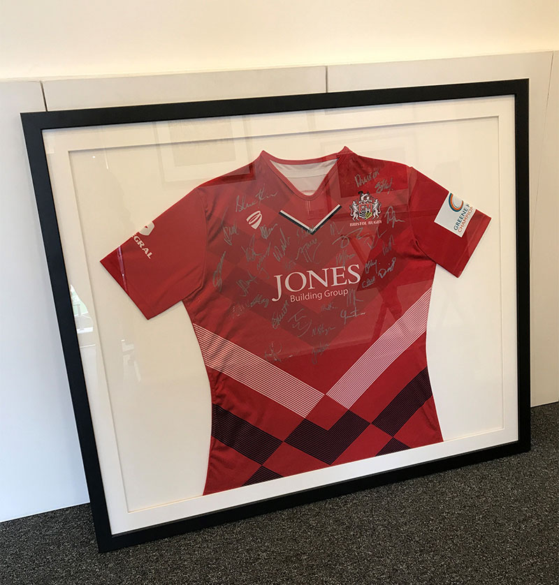 Signed red football shirt in a black frame