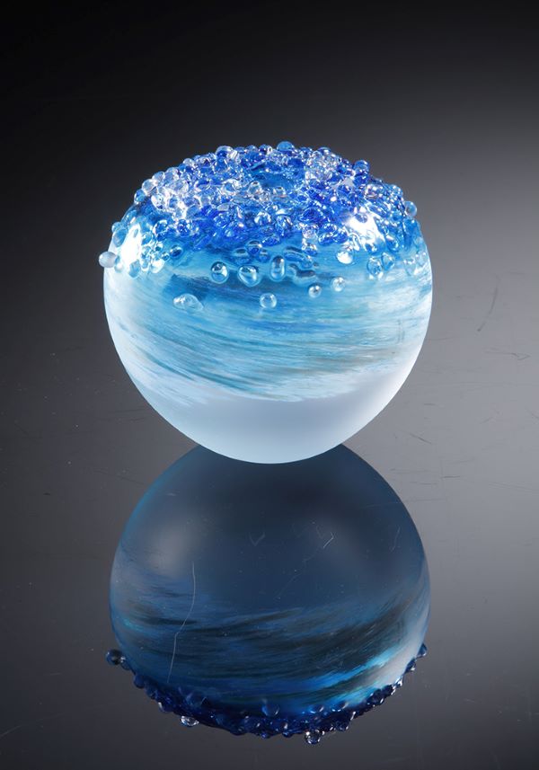 A round glass sculpture of different shads of blue