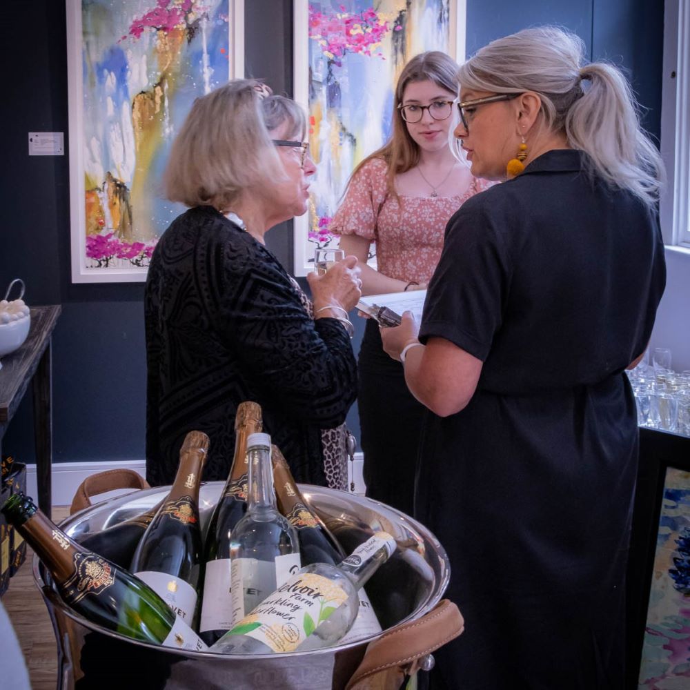 2 women talking in front of the complementary drinks at the pop of colour exhibition