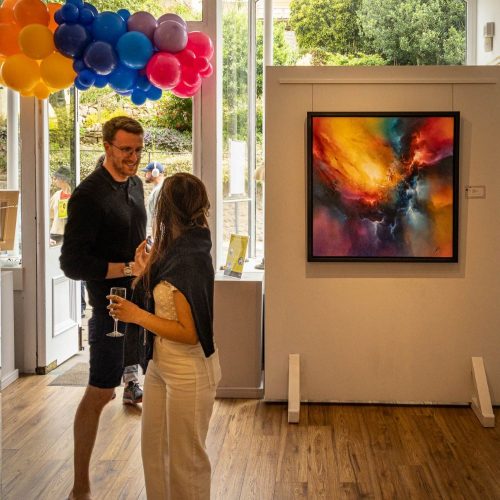 2 people stood under a colourful balloon arch at the pop of colour event